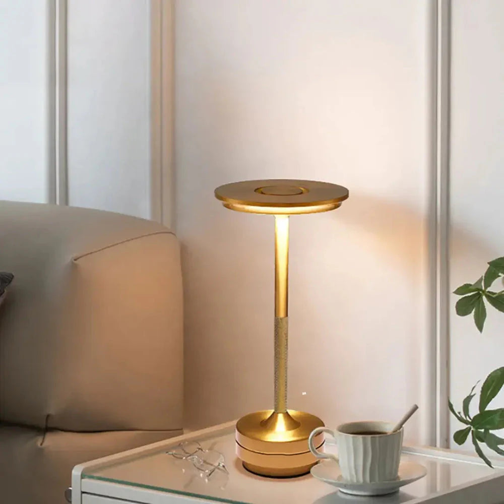 Luminária Halo Touch dourada acesa ao lado de um sofá