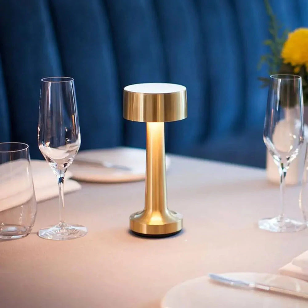 Luminária Lume Touch dourada acesa em mesa de jantar